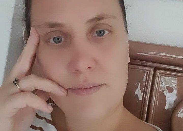 Frau mit kurzem Haar, die nachdenklich mit der Hand am Gesicht sitzt.
